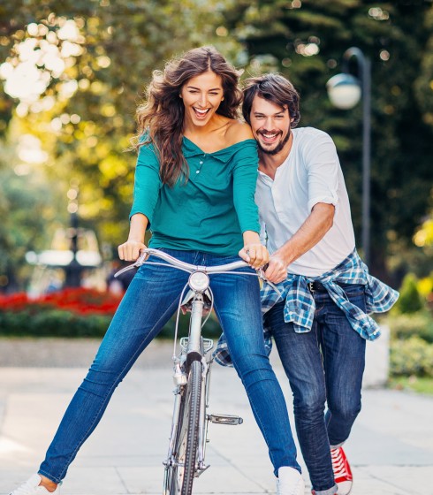 male showing female how to ride a bike in a park