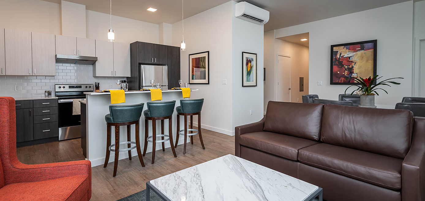 spacious living room with brown couch and three bar stools
