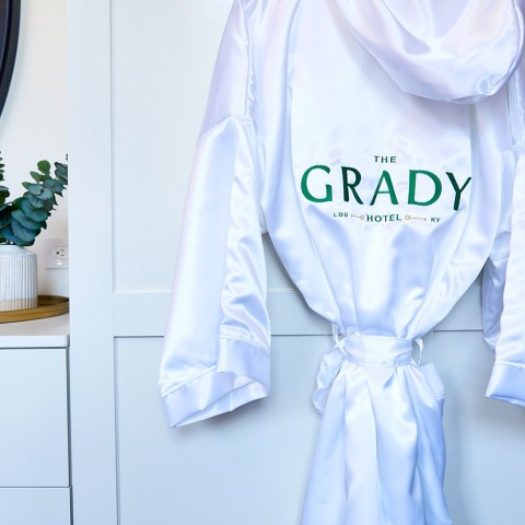 in suite bathroom with a white robe that says the grady hotel