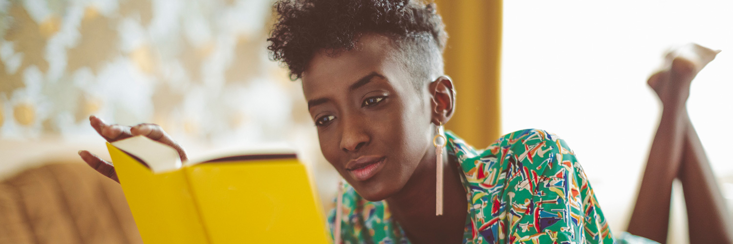 woman wearing a colorful patterned shirt reading a book