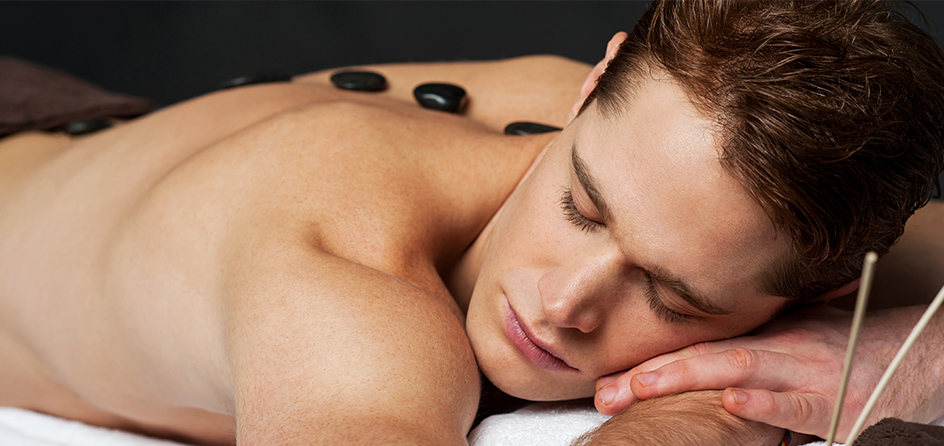man laying down with hot stones on his back