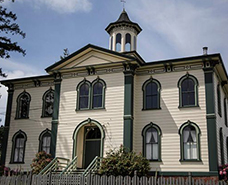 exterior of old beige and green schoolhouse