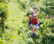 woman zip lining through lush trees