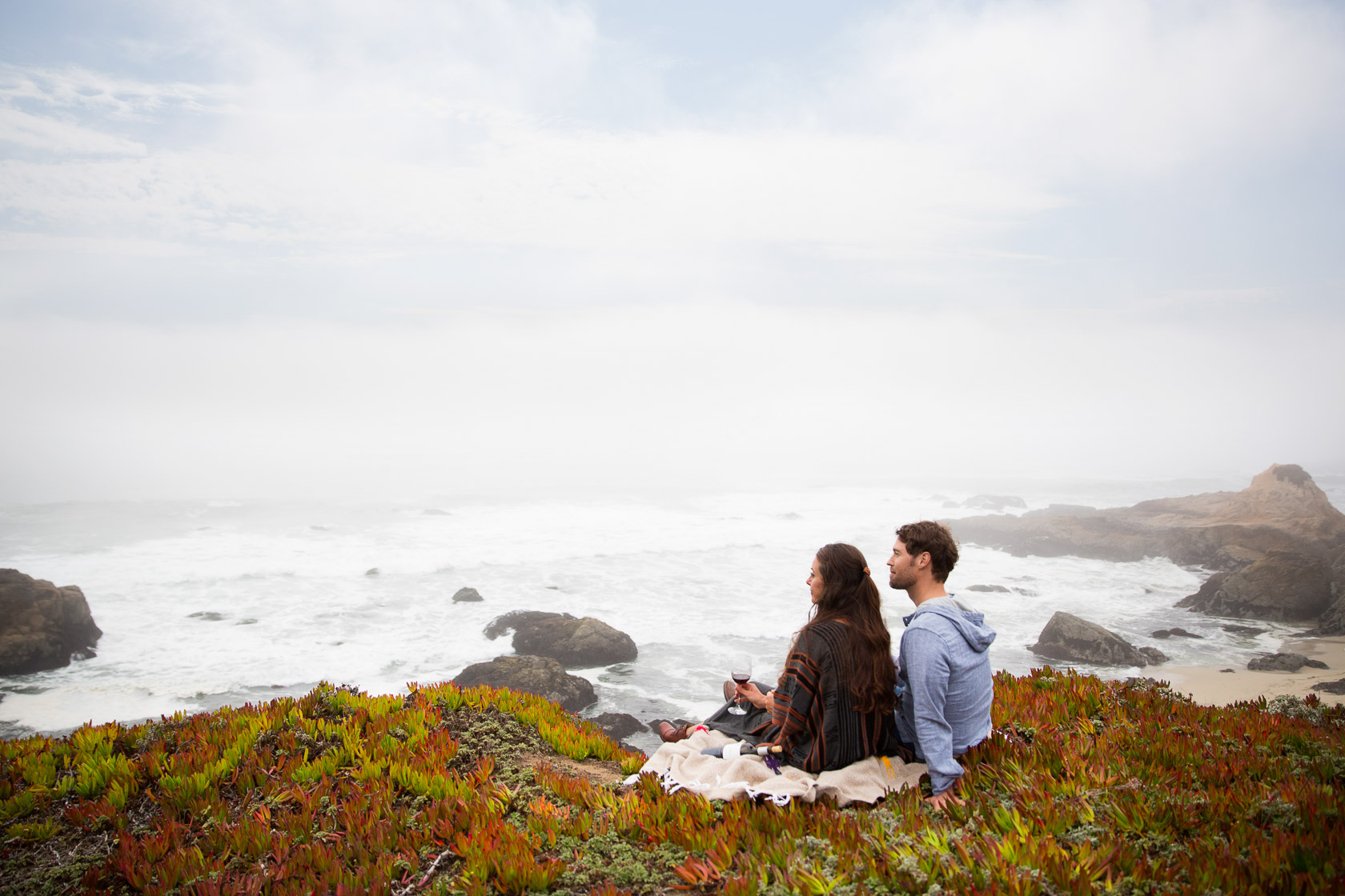couple sitting on a blanket cliffside  