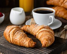 two croissants on a platter with coffee