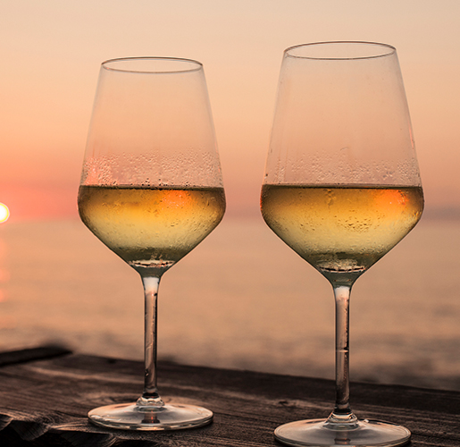 two white wine glasses near the ocean