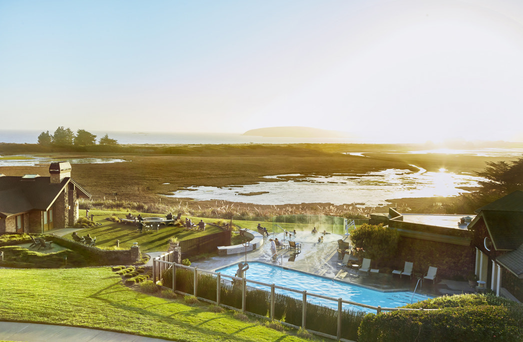 aerial view of the lodge at bodega bay with a blue pool and sunset in the back