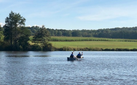 two people rowing in a boat on a lake