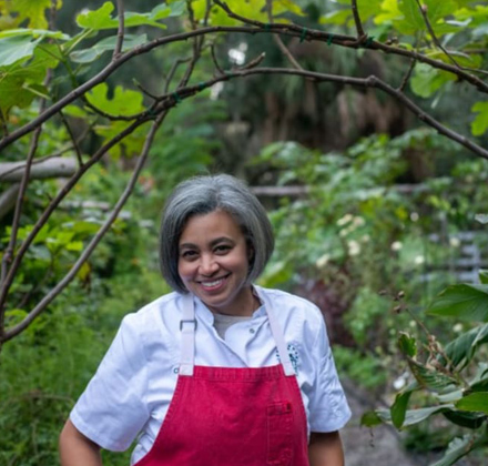 woman smiling while wearing a red apron