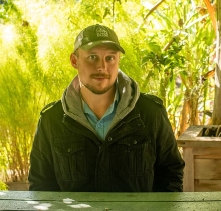 a man sitting at a table with trees as a background
