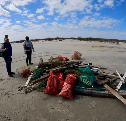 two people standing on the beach with debris next to them