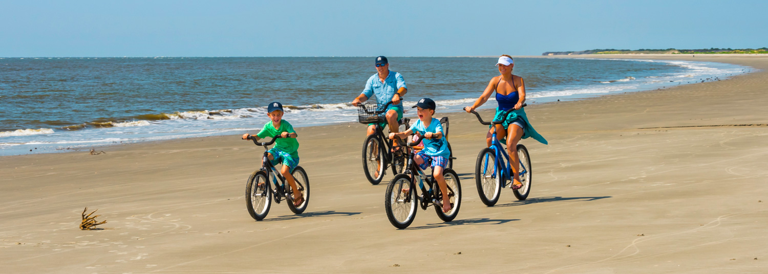 family biking across the beach
