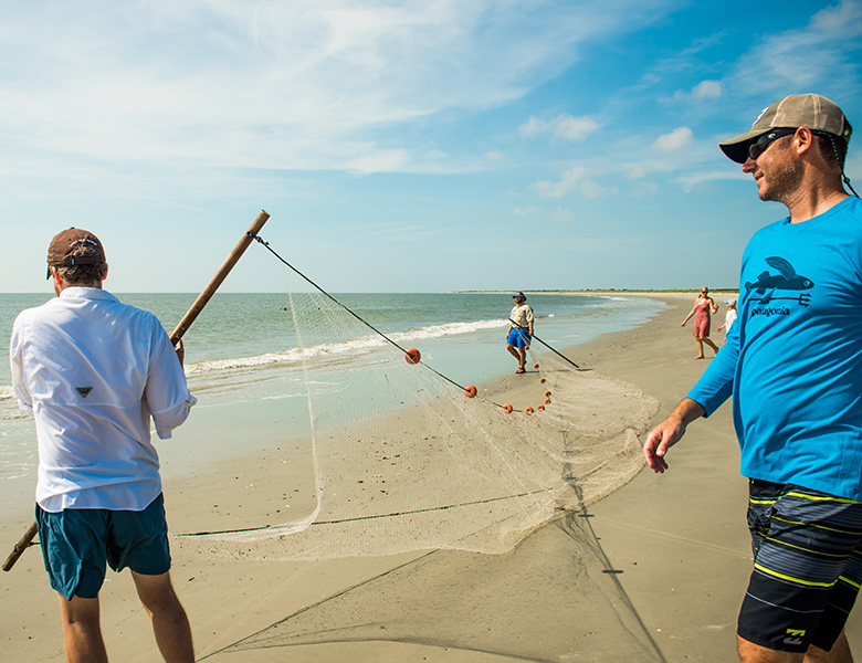 three men holding a net on the beach