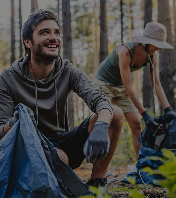two people picking up trash in woods