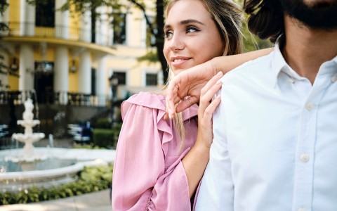 woman with a pink blouse on leaning on a man with a light blue dress shirt 