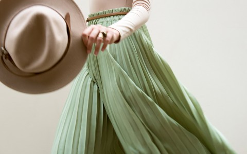 woman wearing green flowy pants while holding a fedora