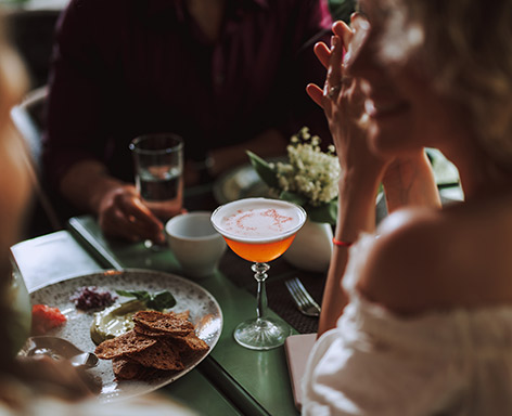 people sitting at a table and drinking an orange martini