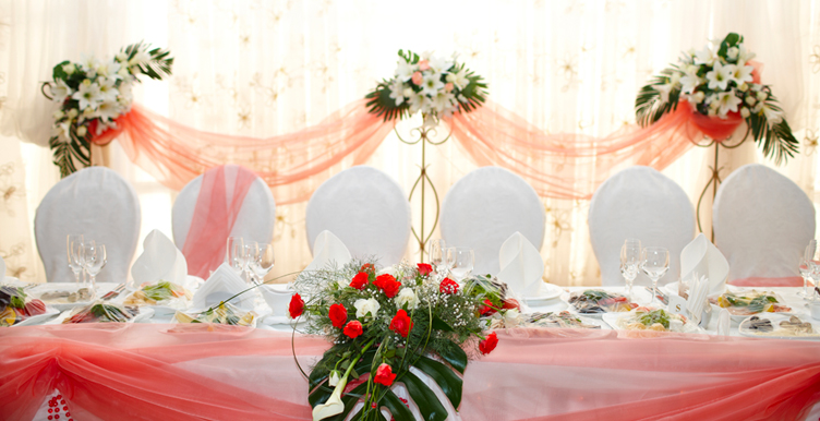 wedding head table with white chairs, pink tablecloth, and flowers