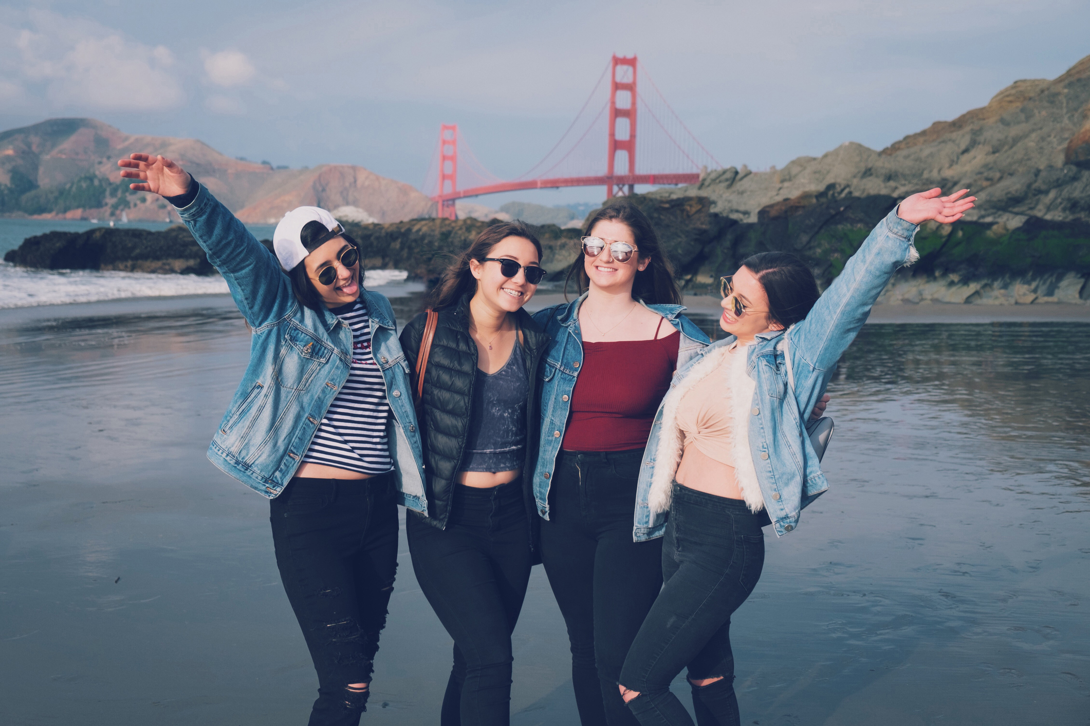 four girls posing at beach with the Golden Gate Bridge in background