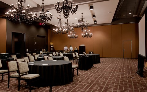 larger venue space with round tables and chandeliers hanging on top