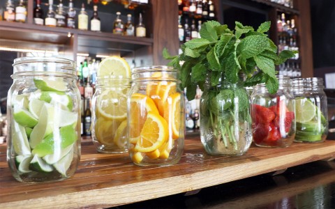 mint leaves, slices of limes, lemons, strawberries and oranges placed in mason jars for the drinks