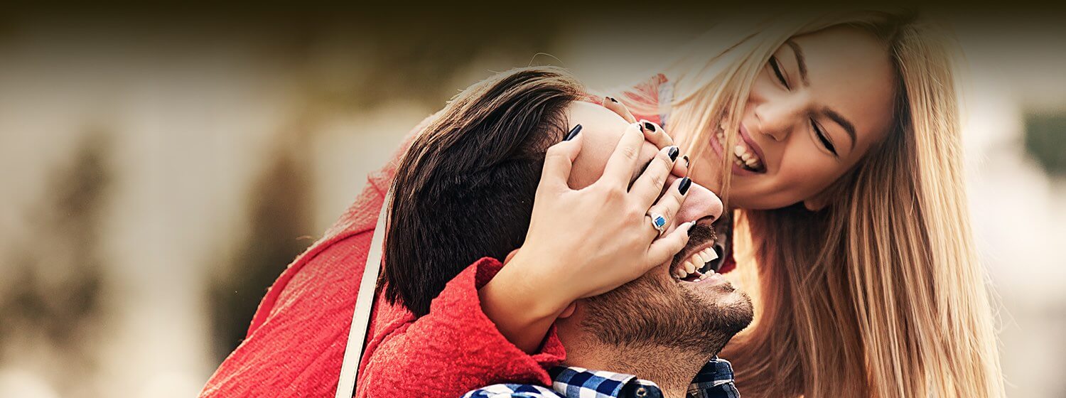 A woman and man having fun together with the woman putting her hands over the mans eyes