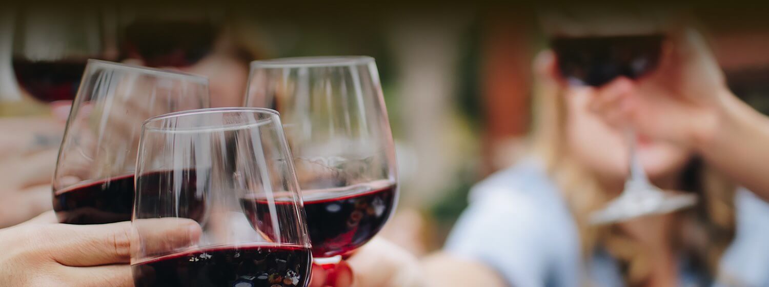 People holding their glasses of red wine together for a cheers