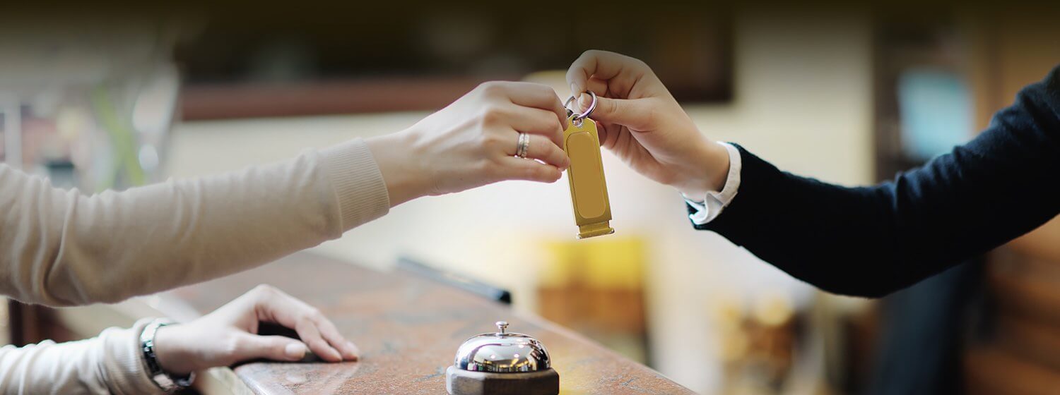 A hotel check in employee handing the a room key over the counter to a guest