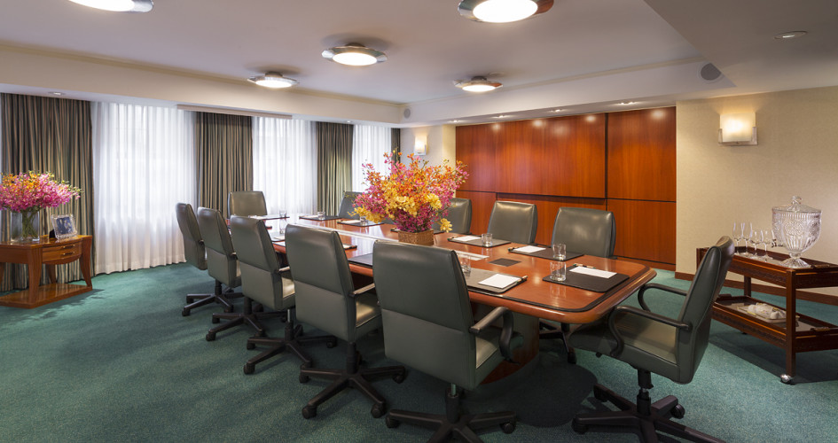 Boardroom image with twelve gray chairs and a wood paneled table