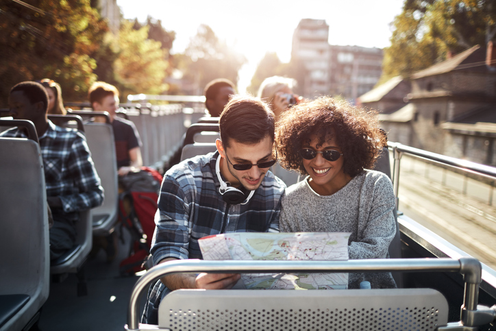 couple on double decker bus tour holding map