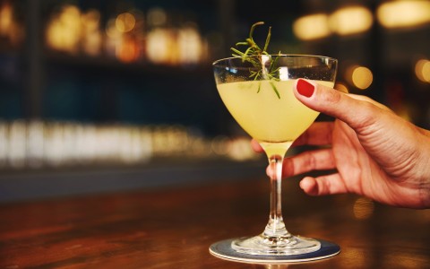 yellow cocktail with sprig of herb