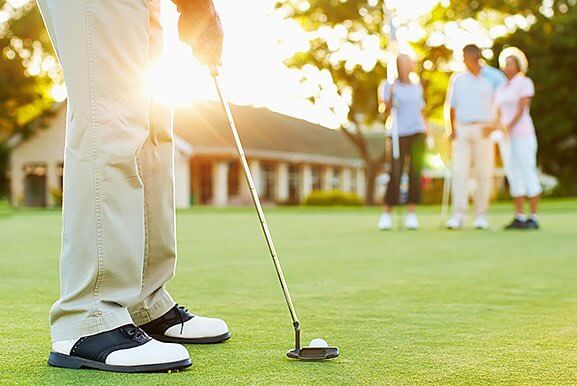 Close up of man ready to hit golf ball with people standing in the background