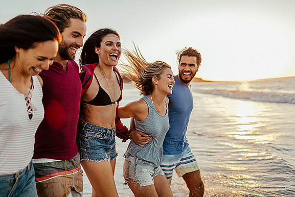 Groups of friends running toward ocean water