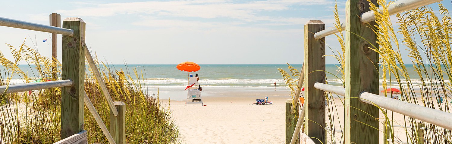 Wooden bridge exit leading to beach with couple standing by water