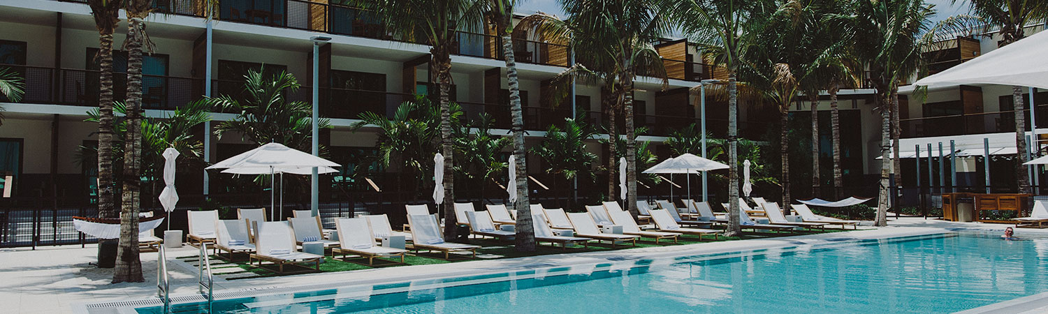 pool with white beach chairs and umbrellas on a sunny day