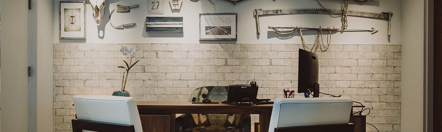 Wooden table with padded chairs & white brick wall in the back
