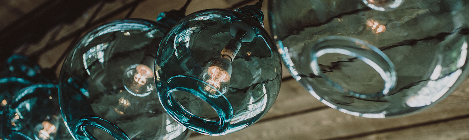 Blue glass round vases with small light bulbs hanging on ceiling
