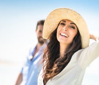 woman smiling at beach with hat