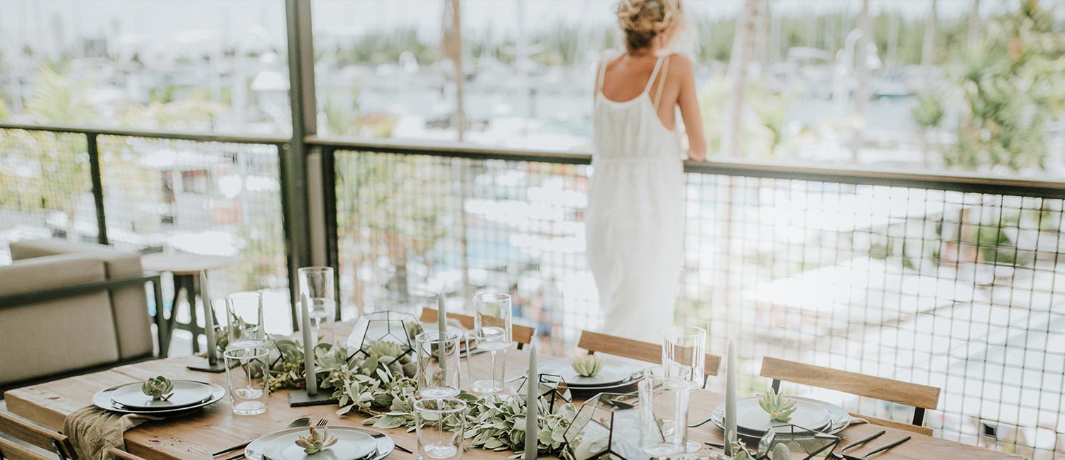 woman standing on balcony overlooking pool with wedding table setup behind her