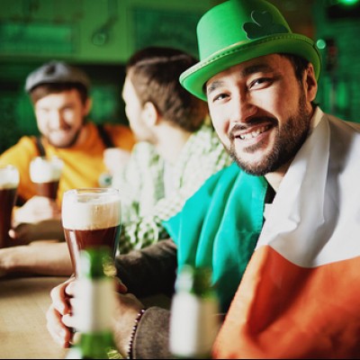 man holding a baar and wearing an irish flag at the bar for sain patricks day