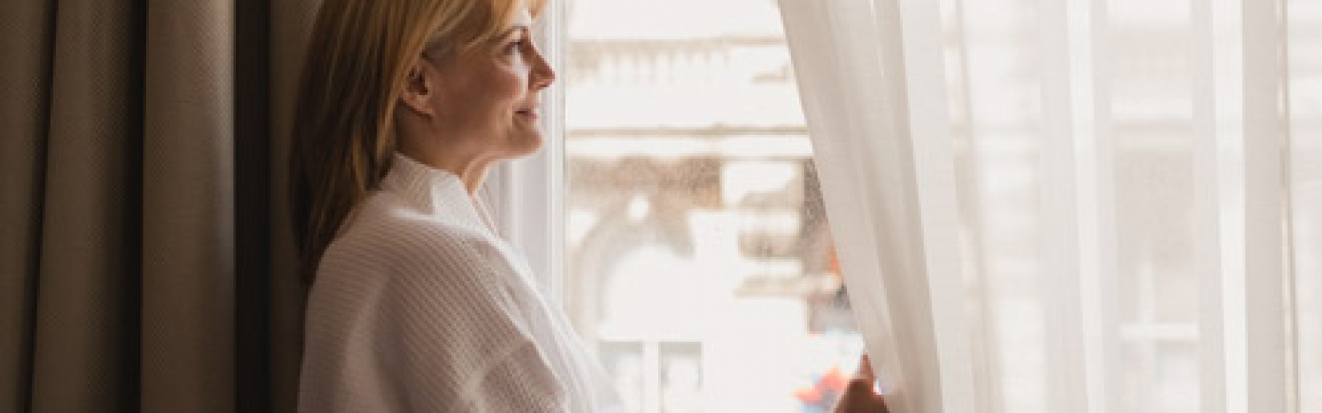 Woman in robe looking out window