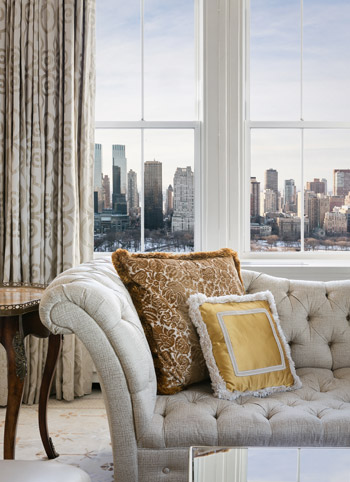 Couch with pillows next to window with city view