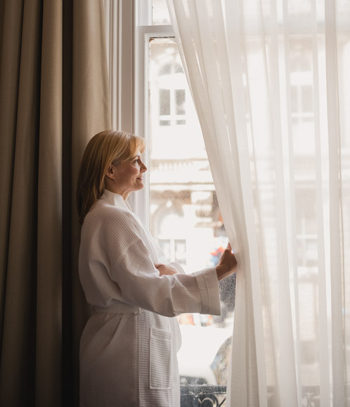 Woman in robe looking out window