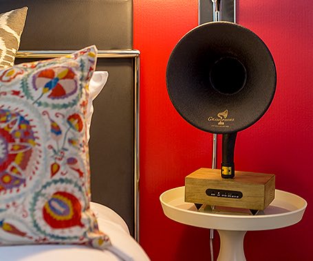 a vintage trumpet speaker on a nightstand next to a bed