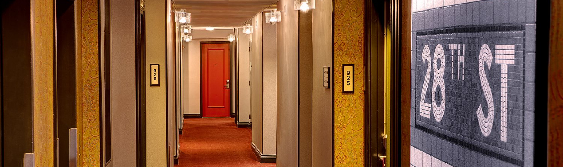 hallway of hotel rooms with gold patterned walls and red doors