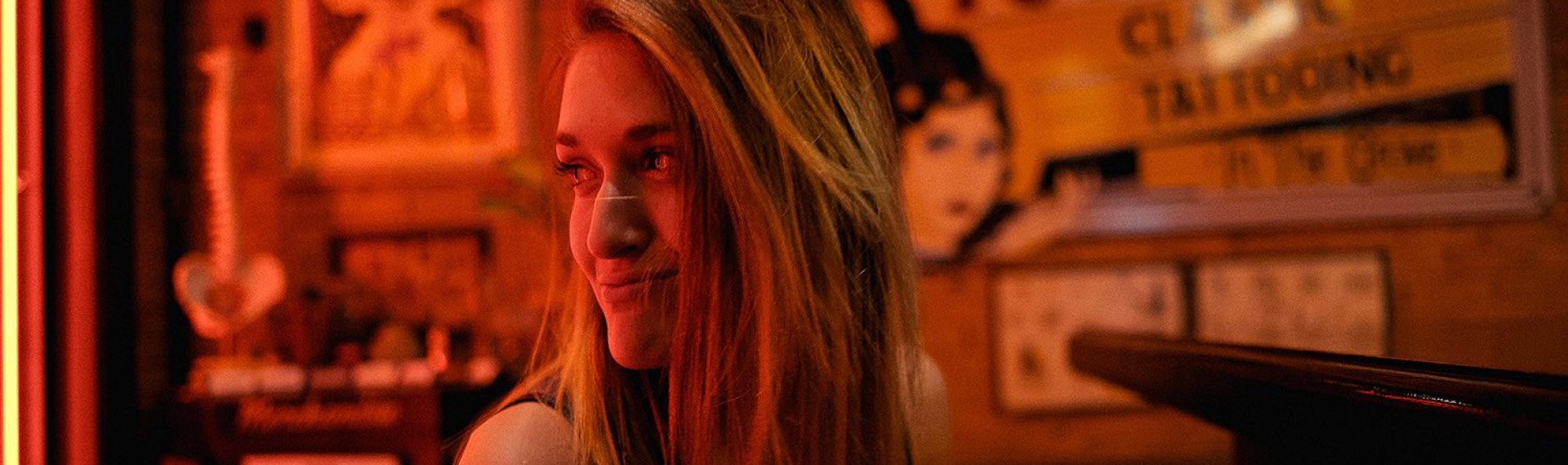 a woman giving a smirk looking off to the side in a room with dim red lights