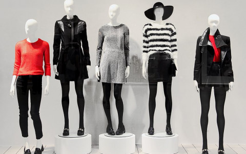 five mannequins dressed in variations of black, white, and red on display at a museum