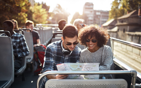 couple on double decker bus tour holding map