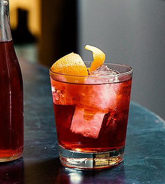 a red cocktail drink with a lemon garnish on top