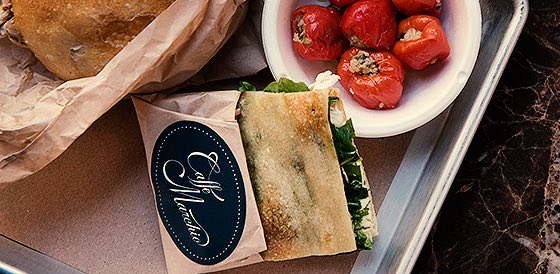 a small panini sandwich next to a bowl of cooked tomatoes